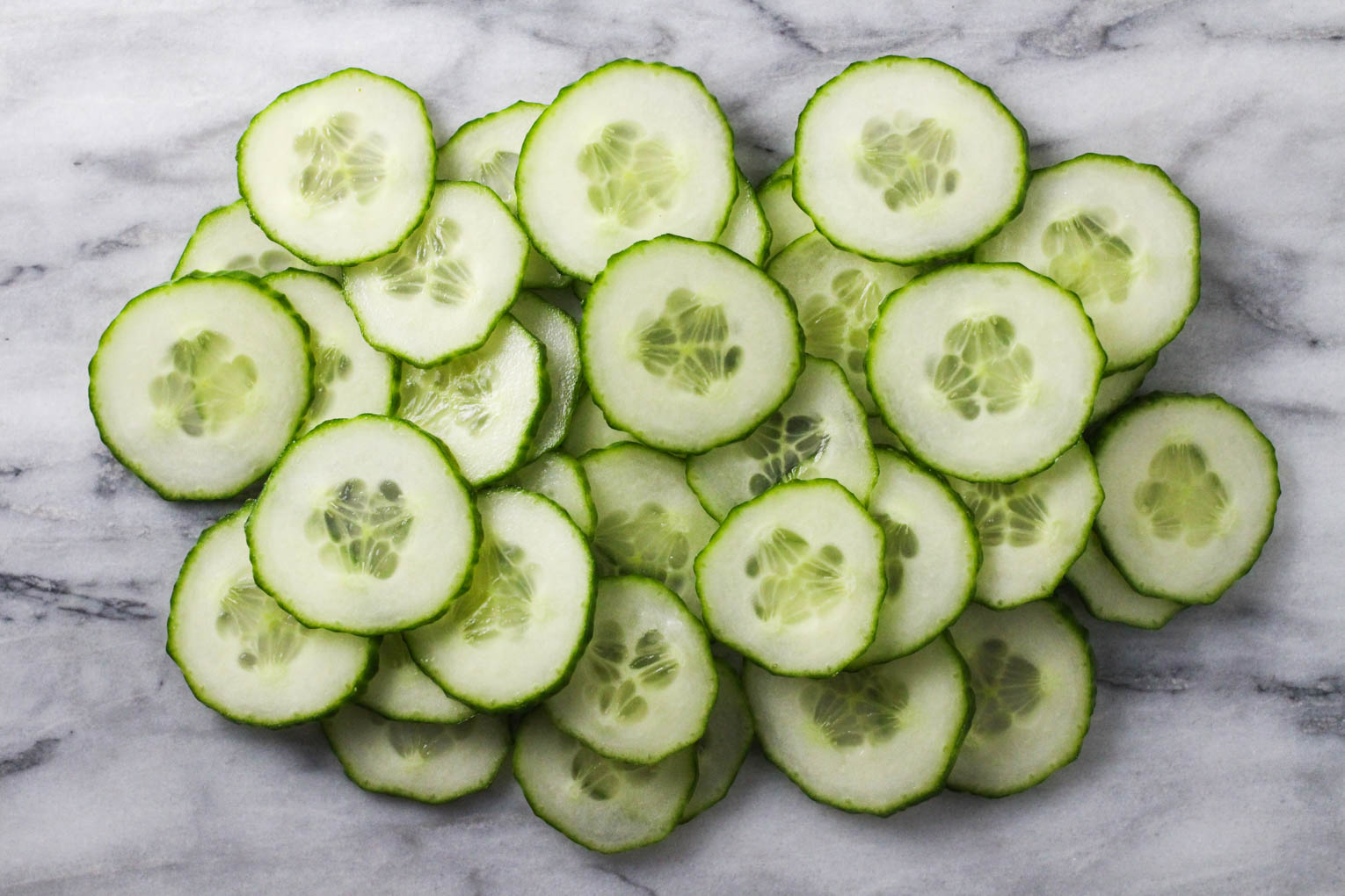 Overhead shot of cucumber slices on marble background.