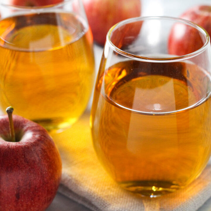 Two glasses of apple juice. Fresh apples in front and behind the glasses.