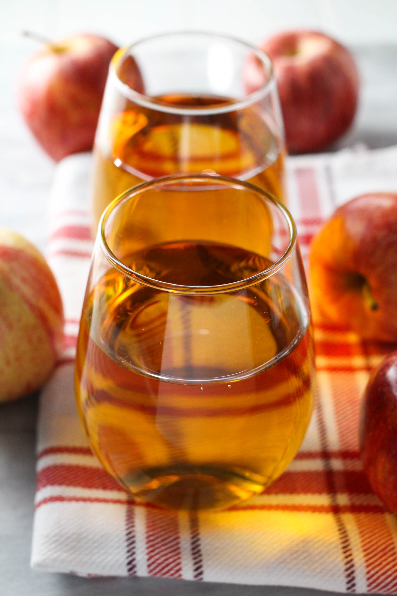 Apple juice in glasses standing on a tea towel. Apples around the tea towel.