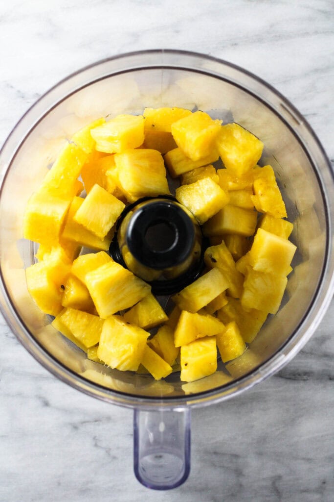 Chopped pineapple pieces in a blender.