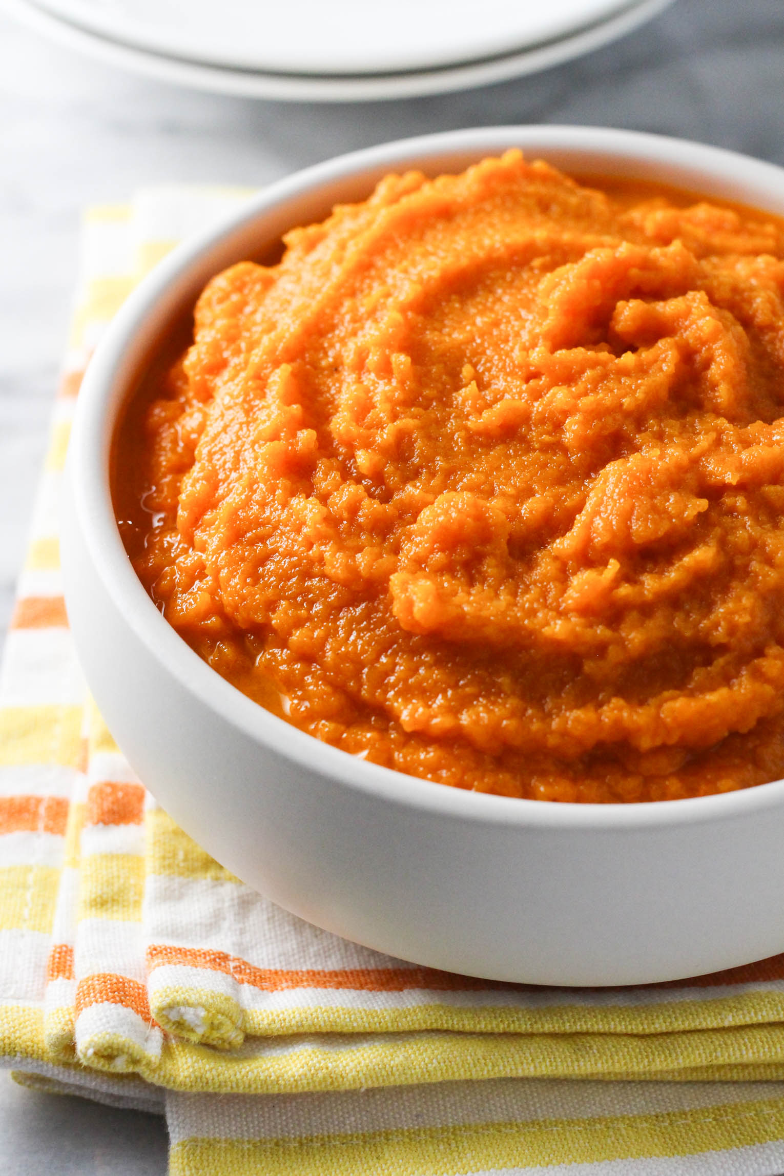 Carrot mash in a bowl standing on a tea towel.