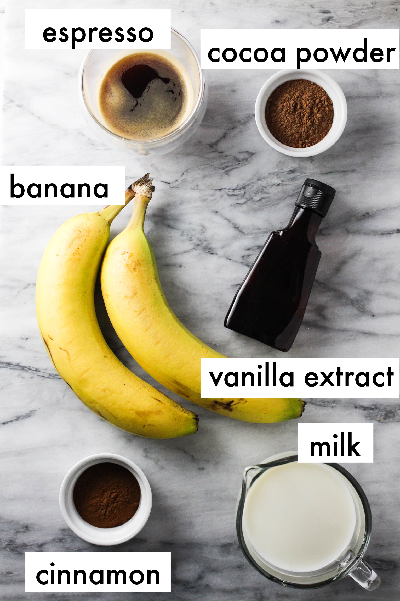 Ingredients for chocolate banana smoothie labeled as follows: espresso, cocoa powder, banana, vanilla extract, milk, cinnamon.