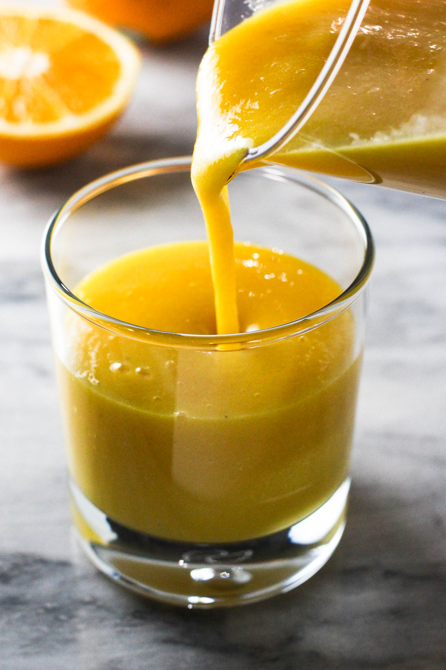 Orange mango smoothie being poured into a glass.