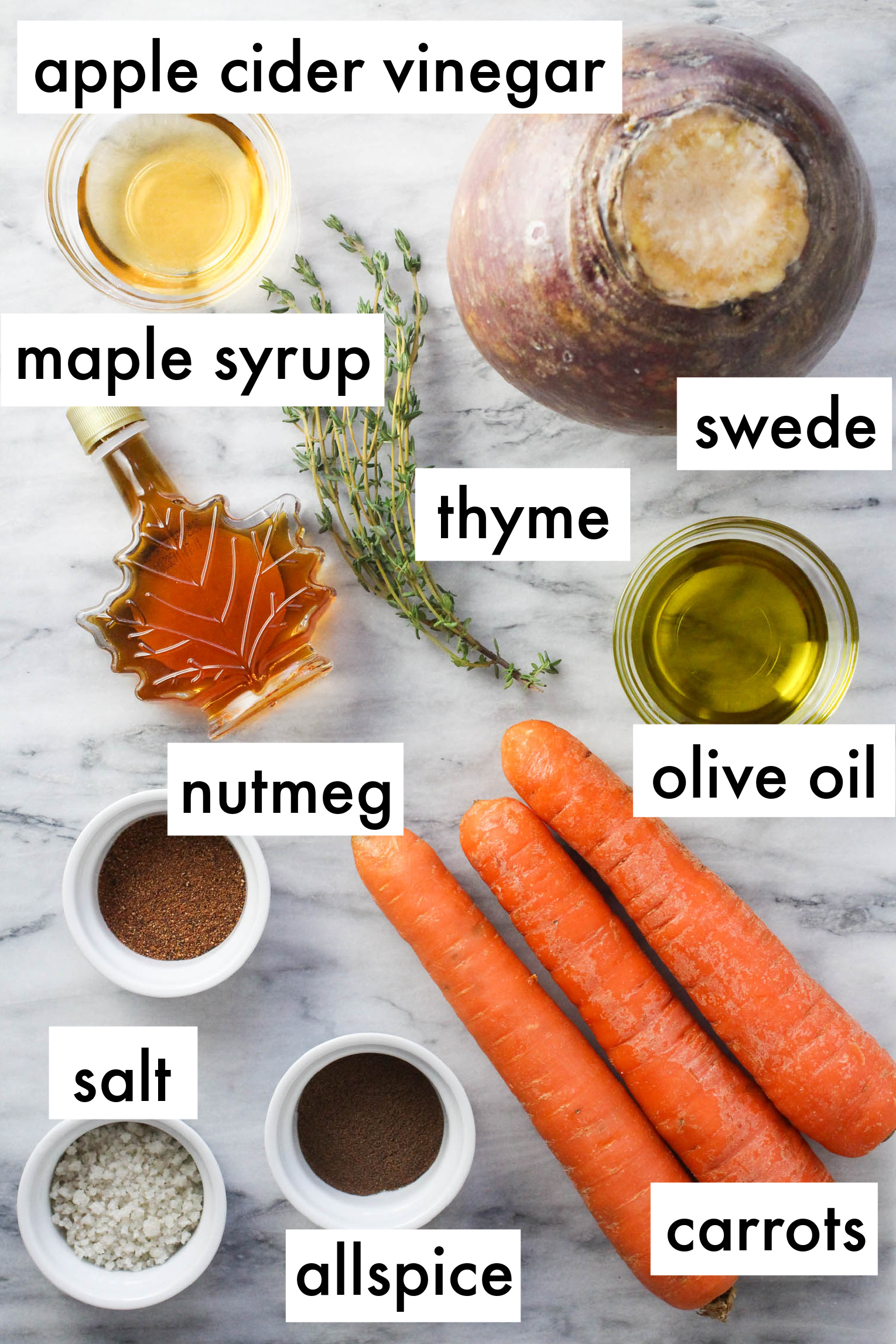 The ingredients for the mash displayed on marble background. The ingredients are labeled as follows: apple cider vinegar, maple syrup, swede, thyme, numeg, olive oil, salt, allspice, carrots.