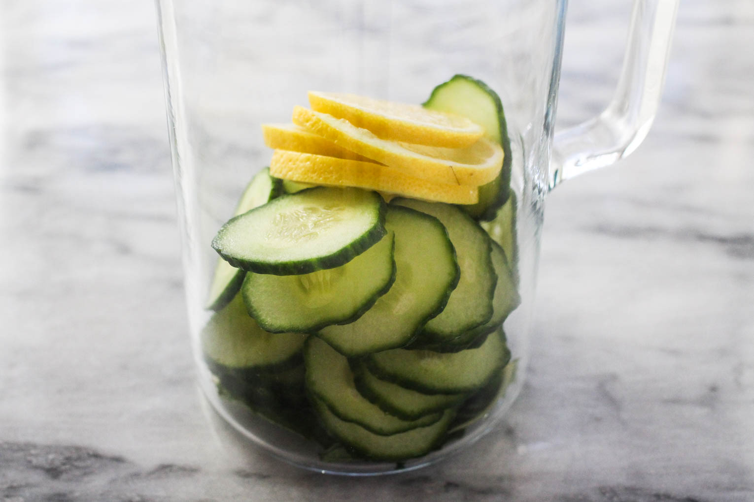 Slices of cucumber and lemon in a pitcher.