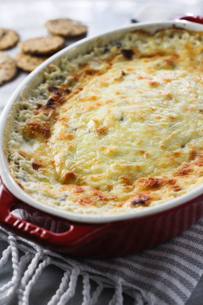 Mashroom dip in a red gratin dish standing on a kitchen towel.