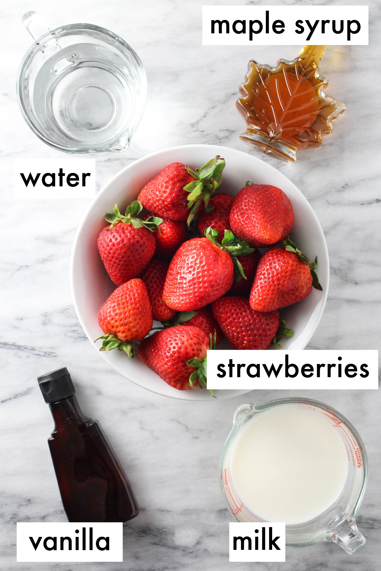 Strawberry milk ingredients displayed on marble background. The ingredients are listed as follows: maple syrup, water, strawberries, vanilla, milk.