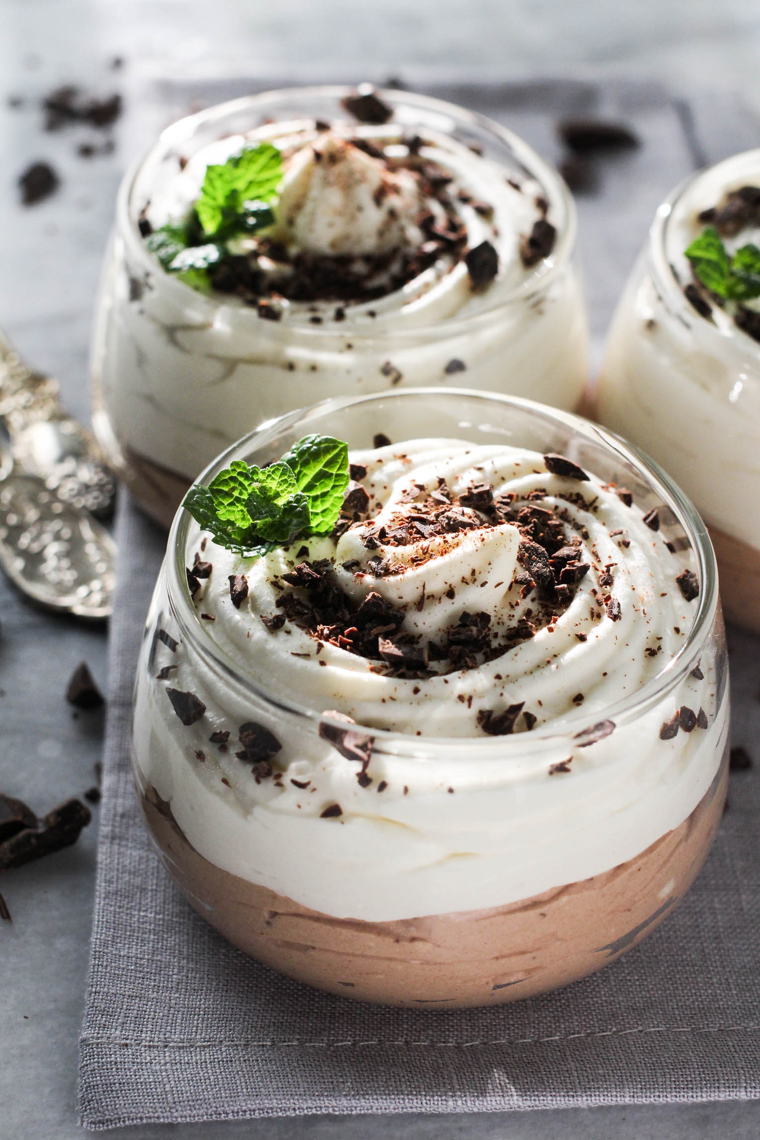 Vanilla and chocolate cottage cheese mousse in dessert glasses garnished with chocolate shavings and mint leaves.