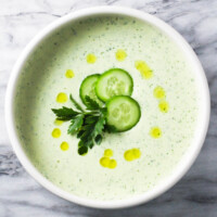 Cottage cheese soup in a bowl, garnished with cucumber slices and parsley.