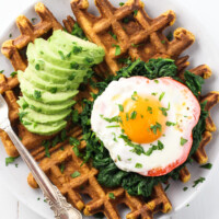 Sweet potato waffles topped with avocado and a fried egg.