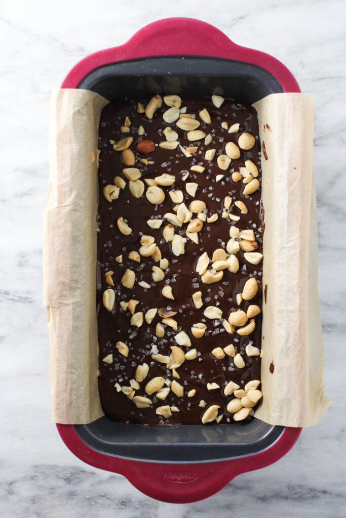 Chocolate layer with peanuts and sea salt in a loaf pan.