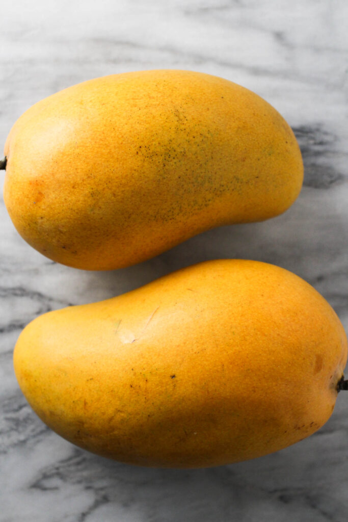 Two mangoes on marble background.