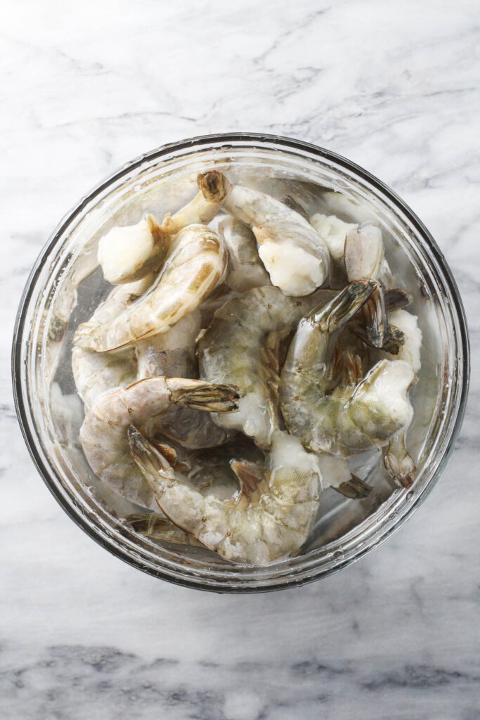 Frozen shrimp in a bowl of water.
