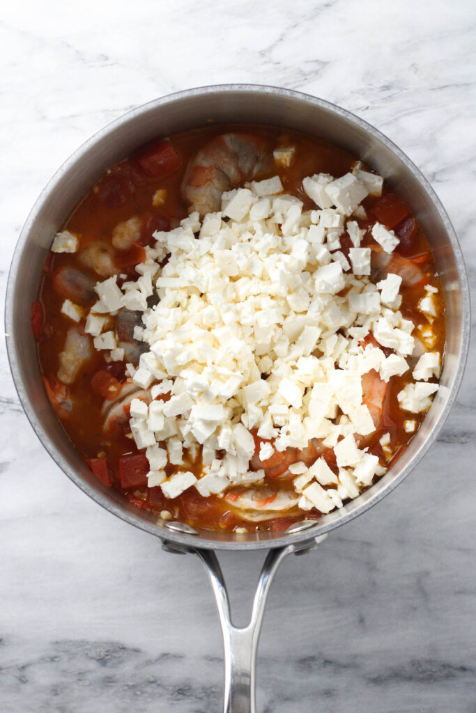 Feta cheese on top of the shrimp in the tomato sauce.