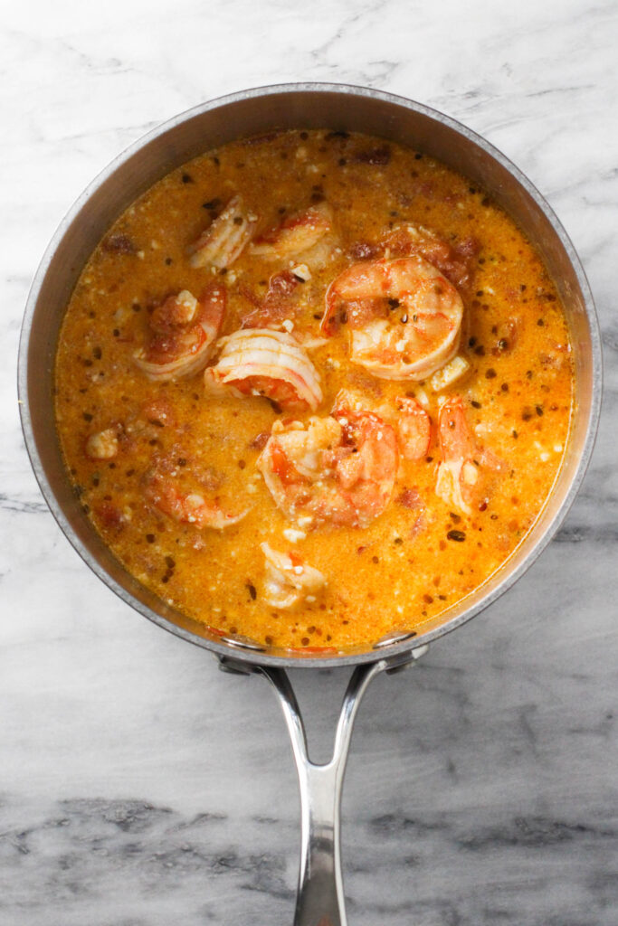 Cooked shrimp with feta and tomatoes in a saucepan.