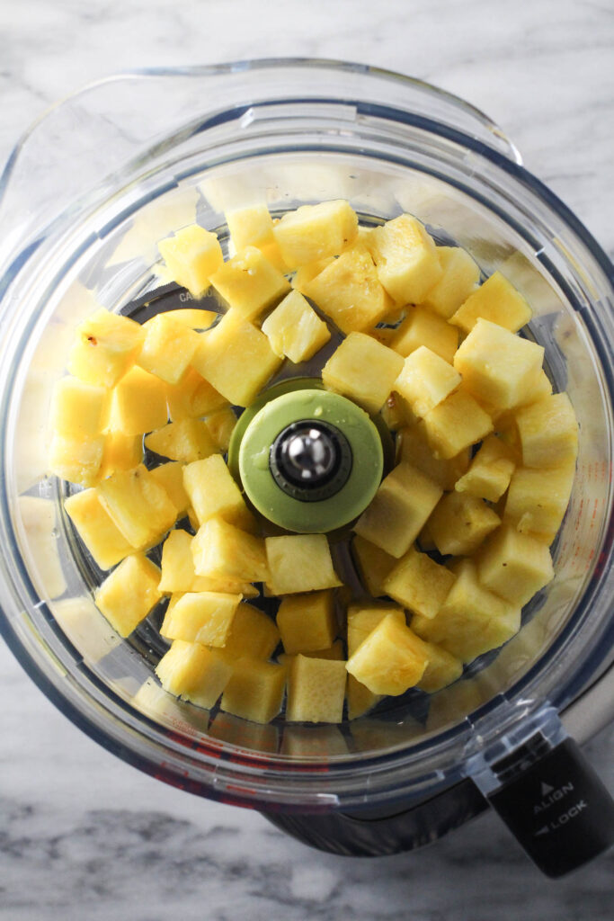 Diced coconut in a bowl of a food processor.