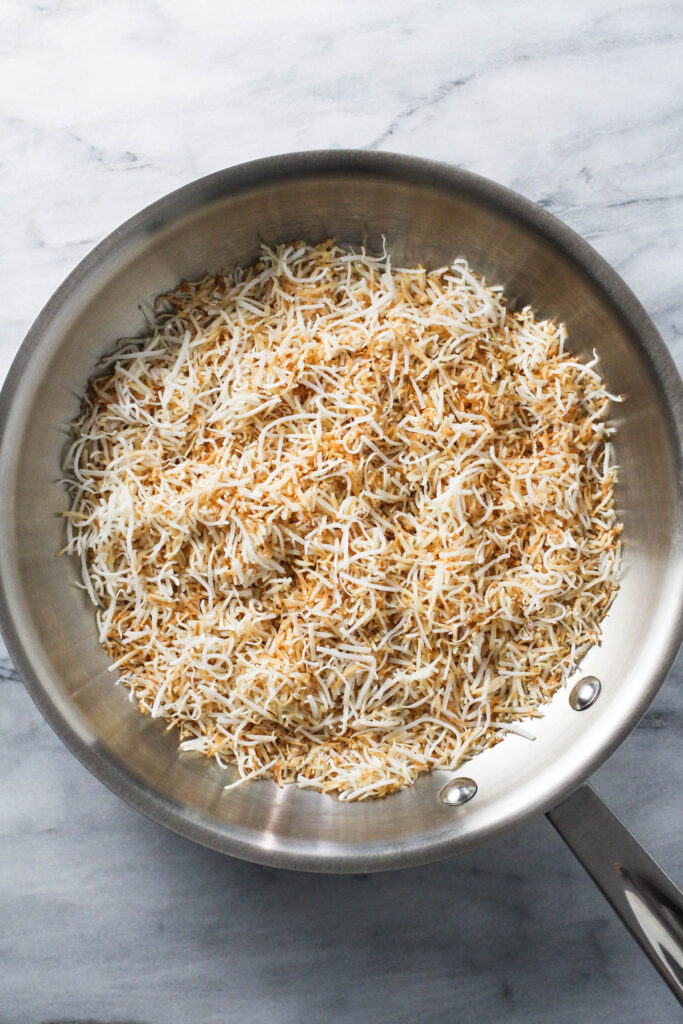 Toasted shredded coconut in a skillet.