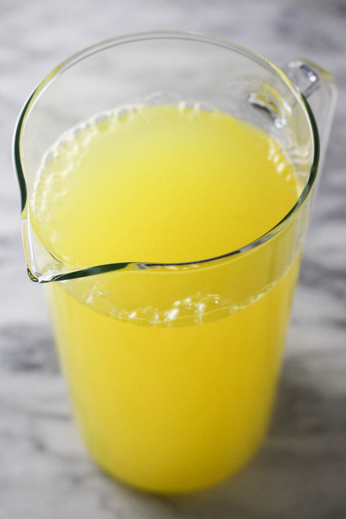 Pineapple coconut water in a pitcher on a marble background.