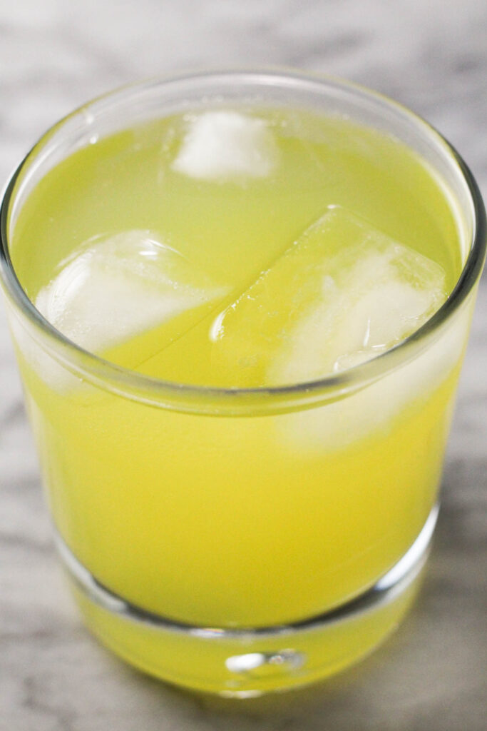 A glass of pineapple coconut water in a glass with ice cubes.