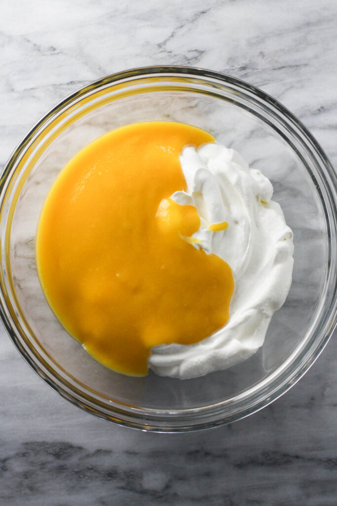 Whipped cream and mango puree in a glass bowl.