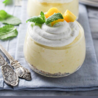 Two dessert bowls with mango mousse standing on a napkin. Belwo the image, there is a text overlay saying: easy mango mousse recipe.