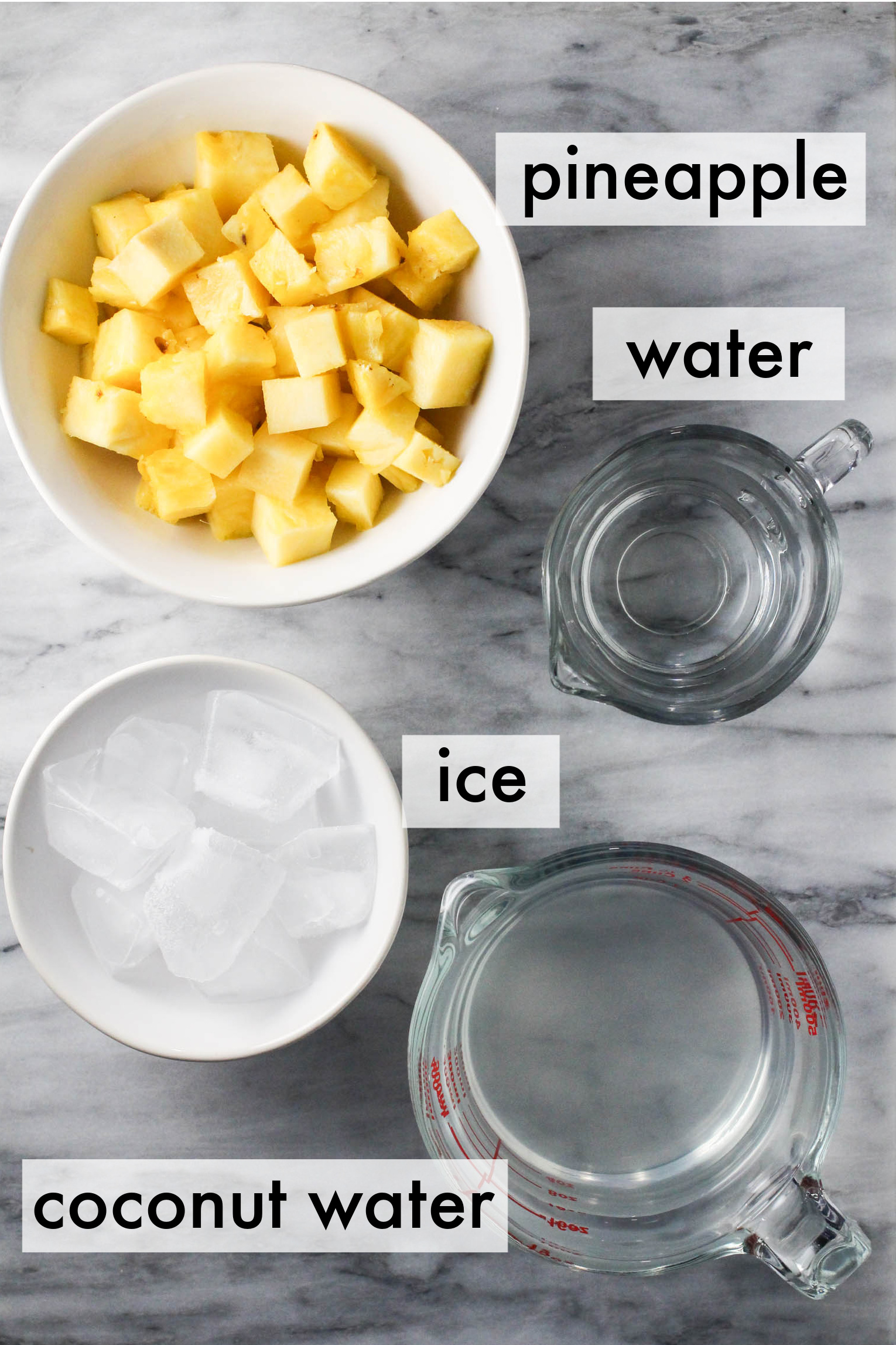 Pineapple coconut water ingredients dispalyed on marble background. The ingredients are labeled as follows: pineapple, water, ice, coconut water.