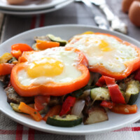 Two eggs with sauteed vegetables on a plate.