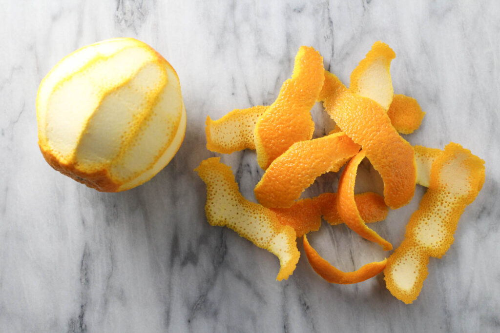 A peeled orange and orange peel on marble background.