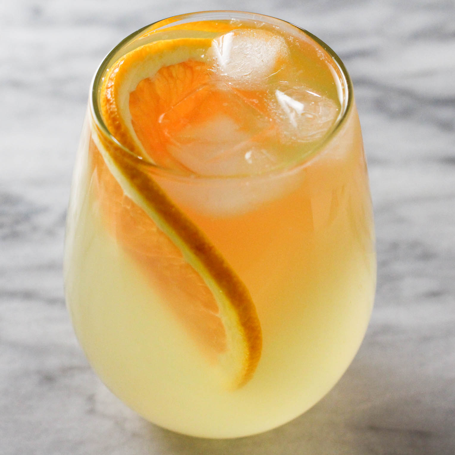 A glass for orange water with ice and orange slices.