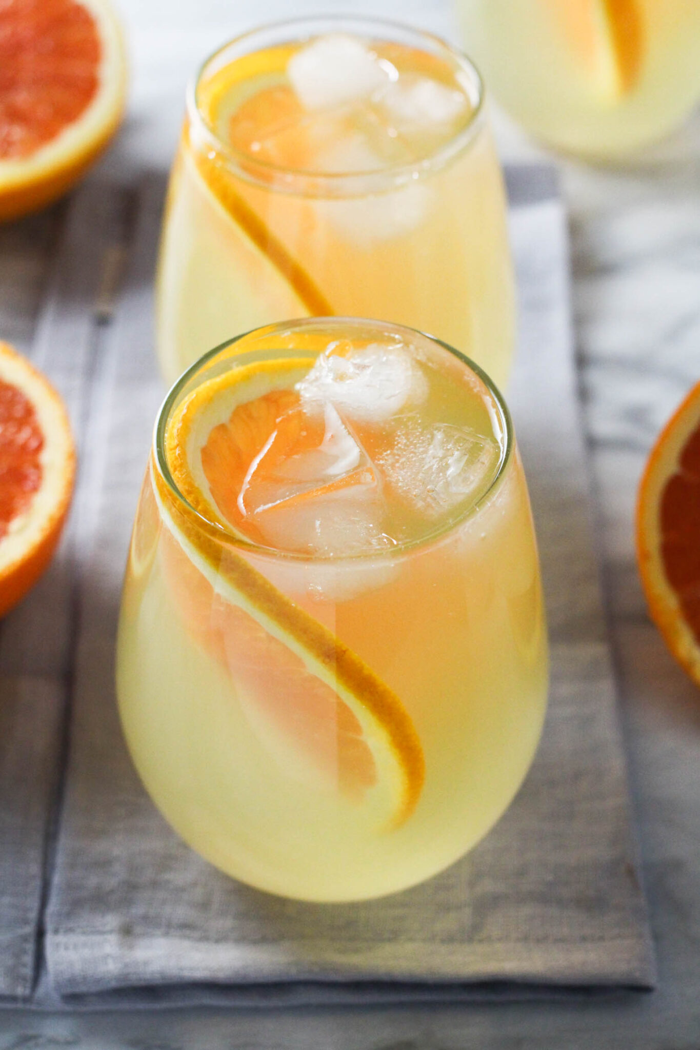 Two glasses of orange water with ice and orange slices.
