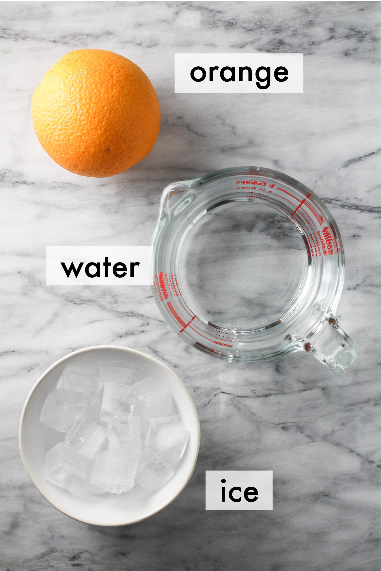 Orange water ingredients on marble background. The ingredients are labeled as follows: orange, water, ice.