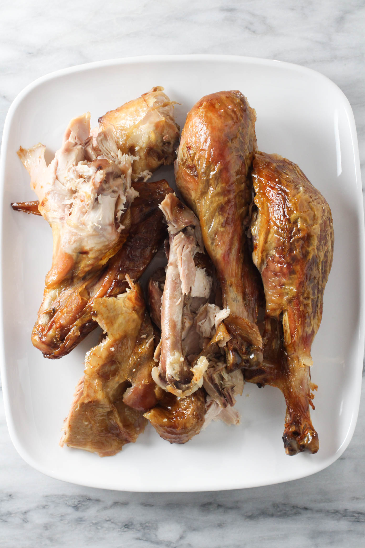 Leftover roasted turkey meat and bones on a white plate.