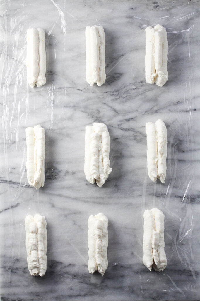 Cheese mixture piped onto plastic wrap in bar shapes.