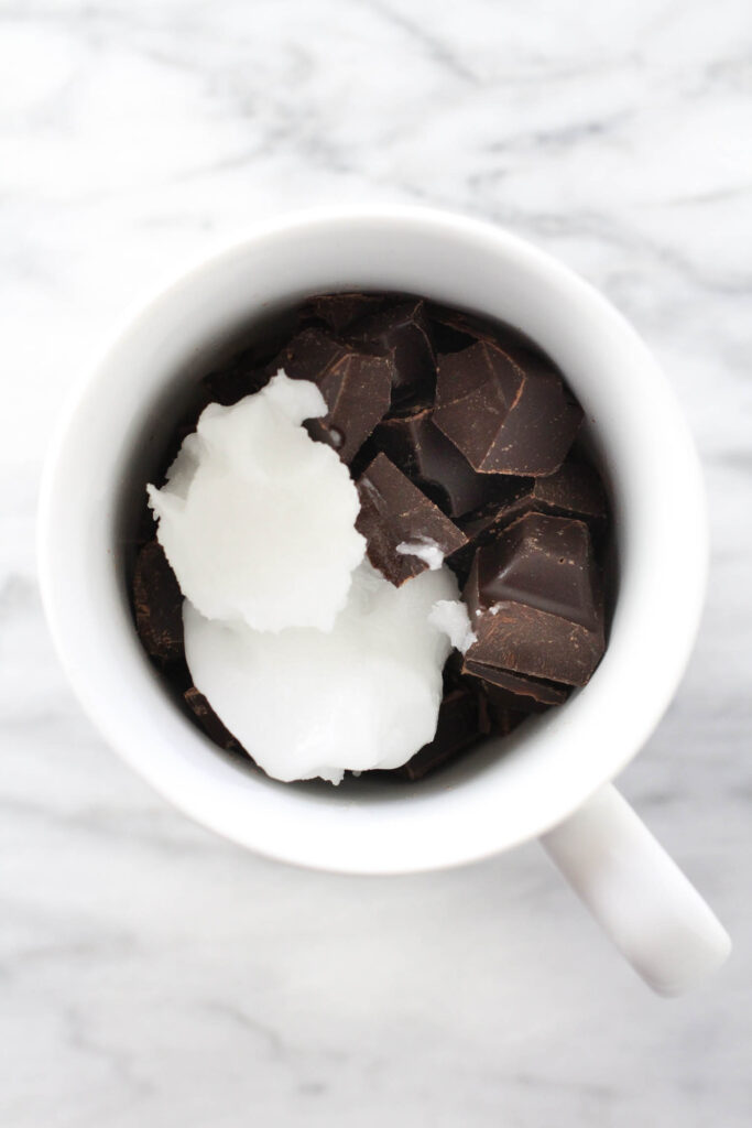 Chocolate chunks and coconut oil in a mug.