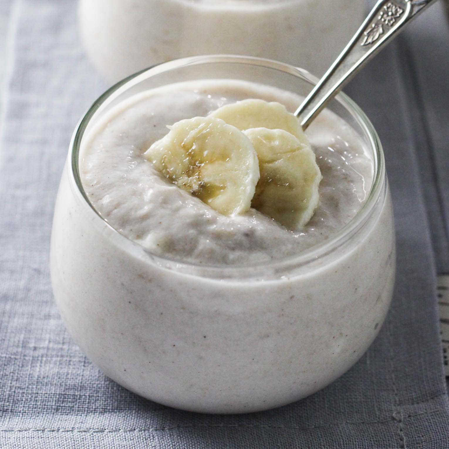 Banana yogurt in a glass dessert bowl, garnished with banana slices.