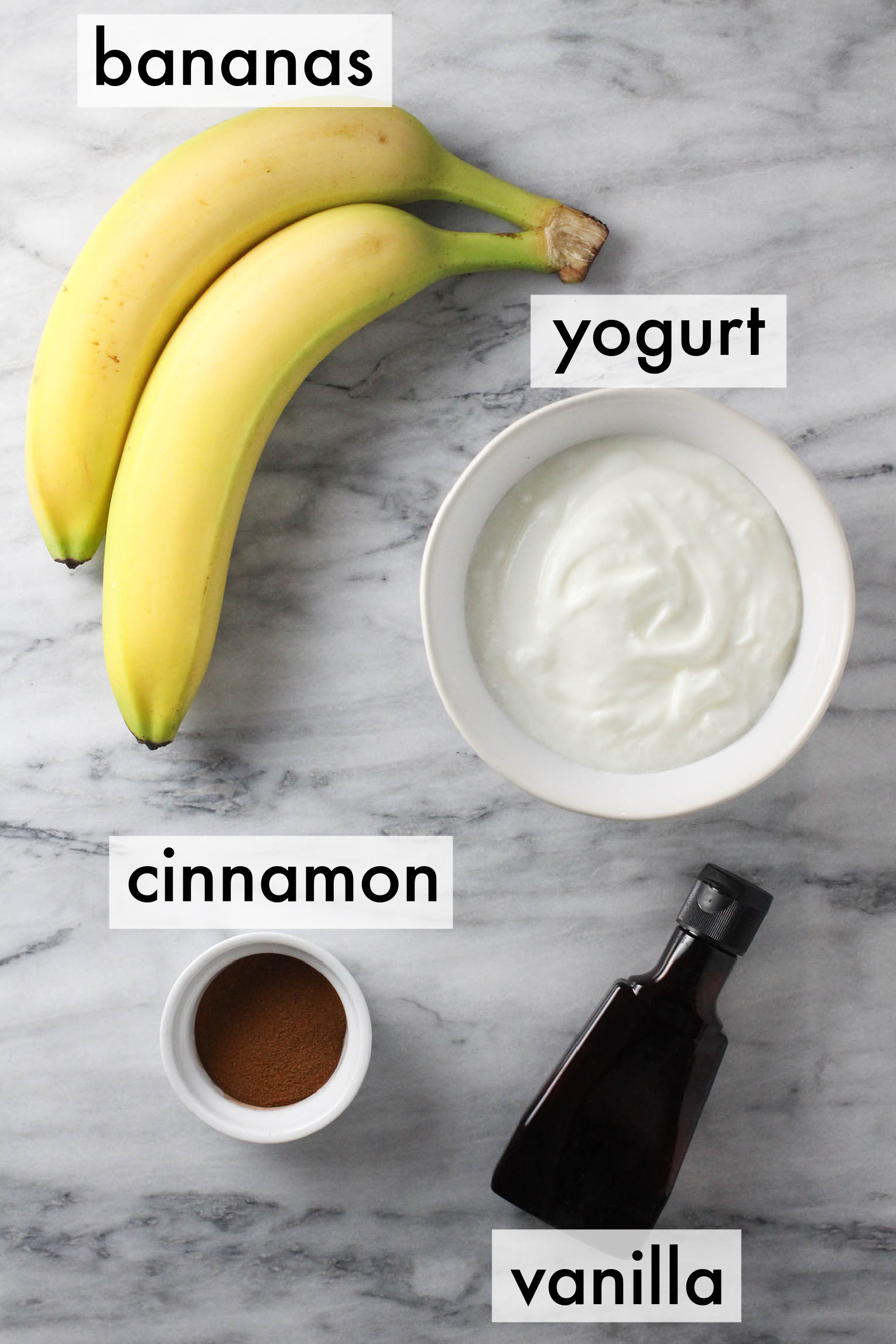 Ingredients for banana yogurt displayed on marble background. The ingredients are labeled as follows: banana, yogurt, cinnamon, vanilla.