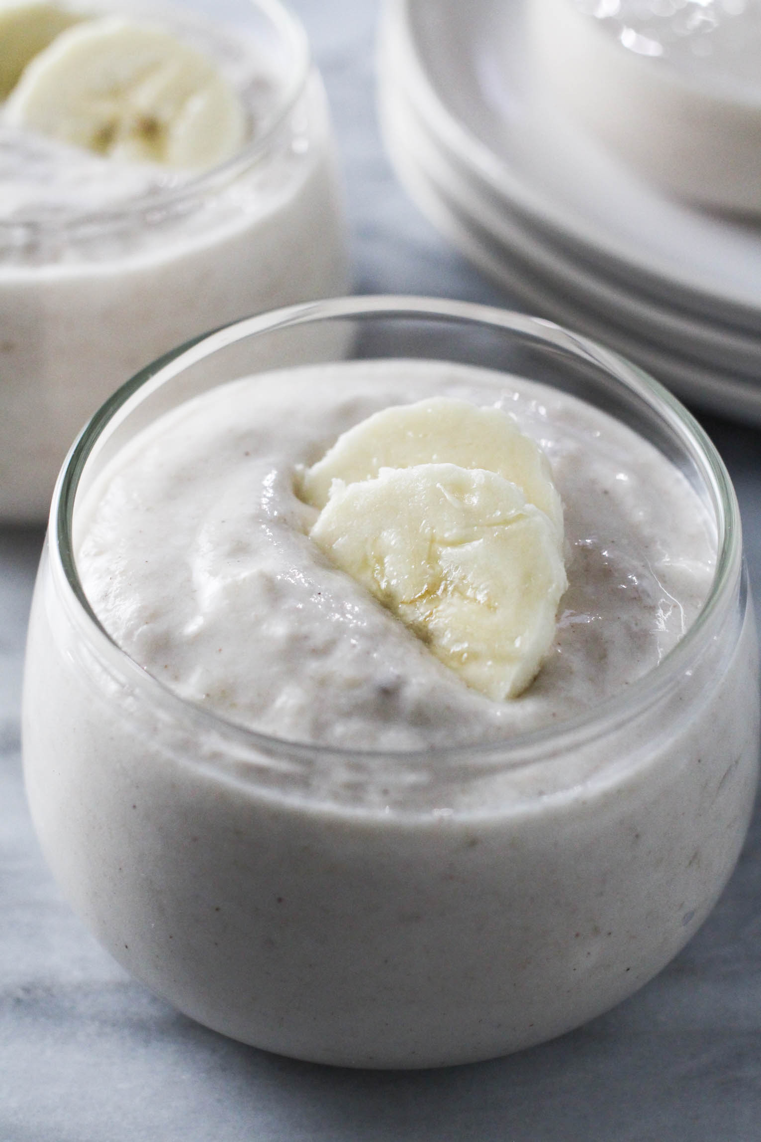 Banana yogurt in a glass dessert bowl, garnished with banana slices.