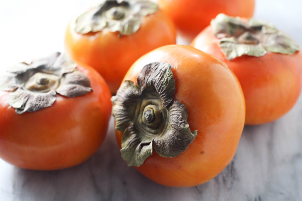 Close up of Fuyu persimmons on marble background.