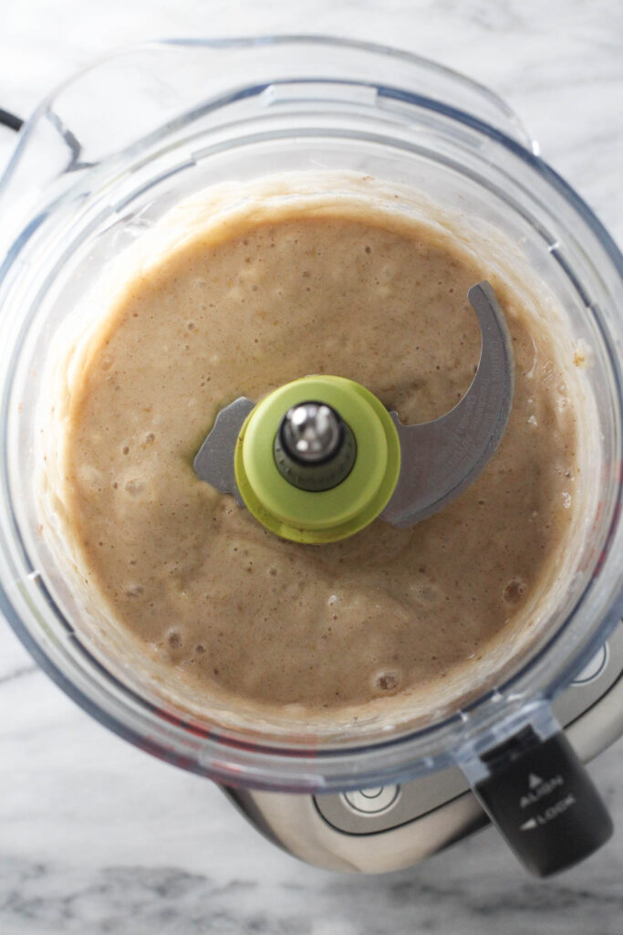 Pureed banana in a bowl of a food processor.