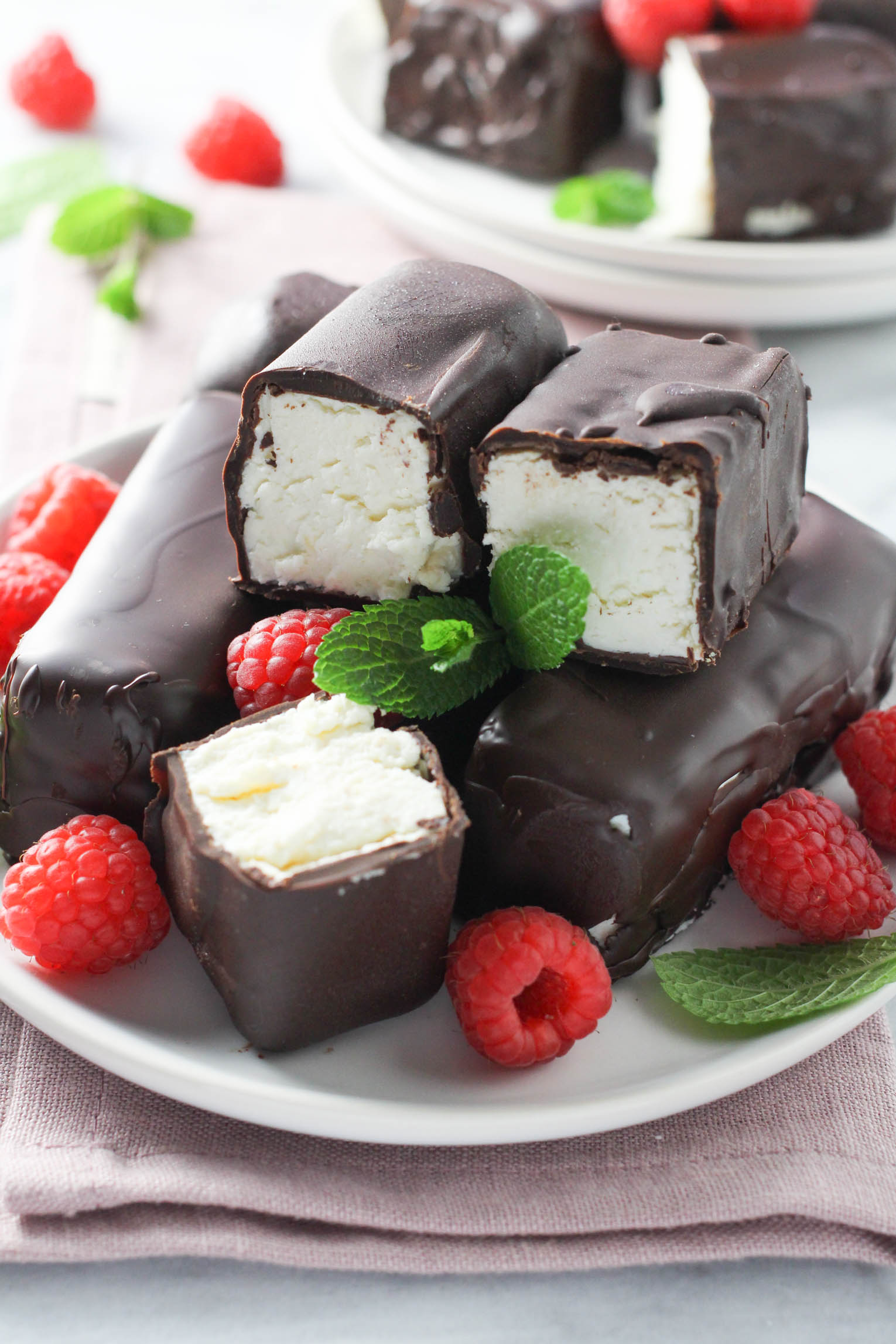 Chocolate glazed syrok bars on a plate, garnished with raspberries and mint leaves.