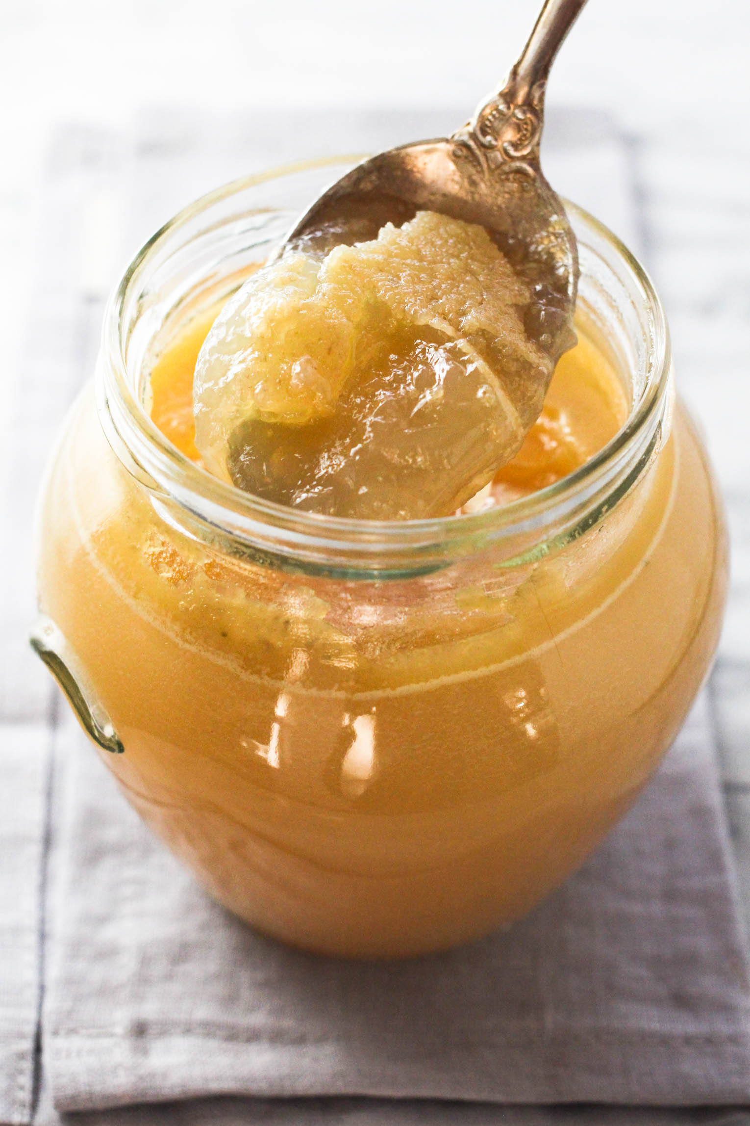 Gelled turkey bone broth being scooped with a spoon out of a jar.