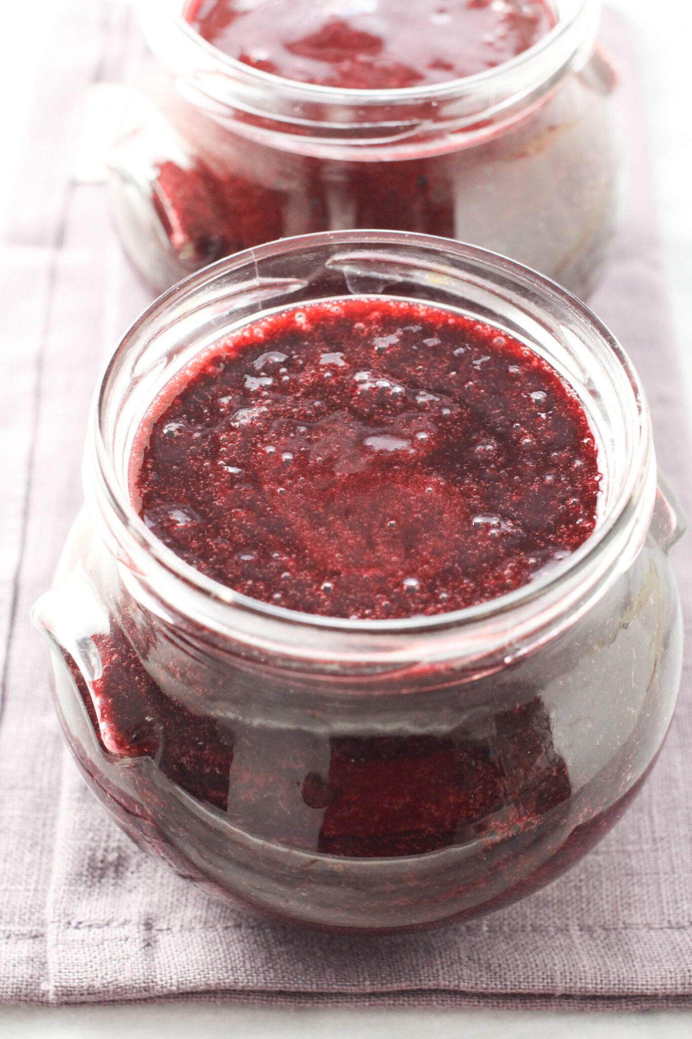 Blackberry puree in a glass jar standing on a linen napkin.