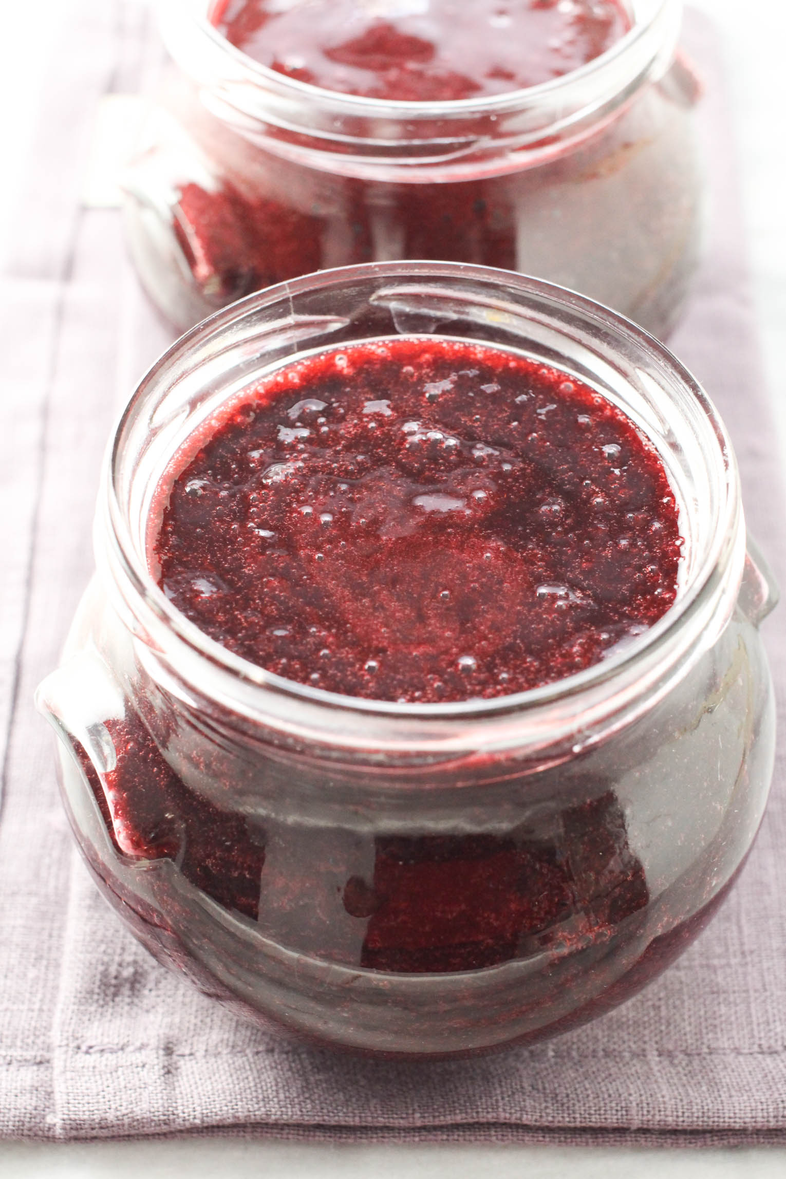 Blackberry puree in a glass jar standing on a linen napkin.