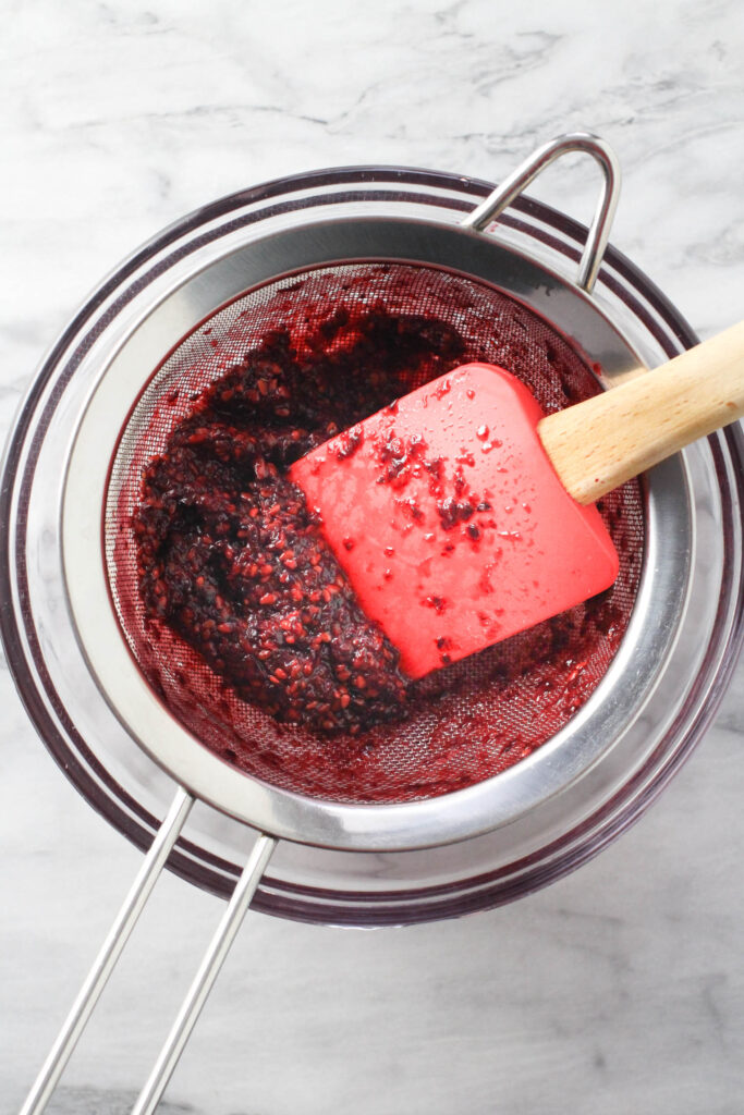 Blackberry seeds in a fine mesh sieve placed over a blowl.