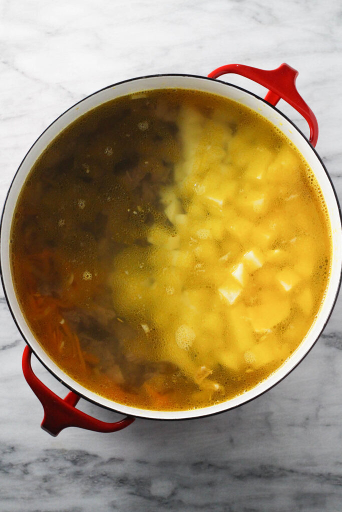 All ingredients in a soup pot standing on marble background..