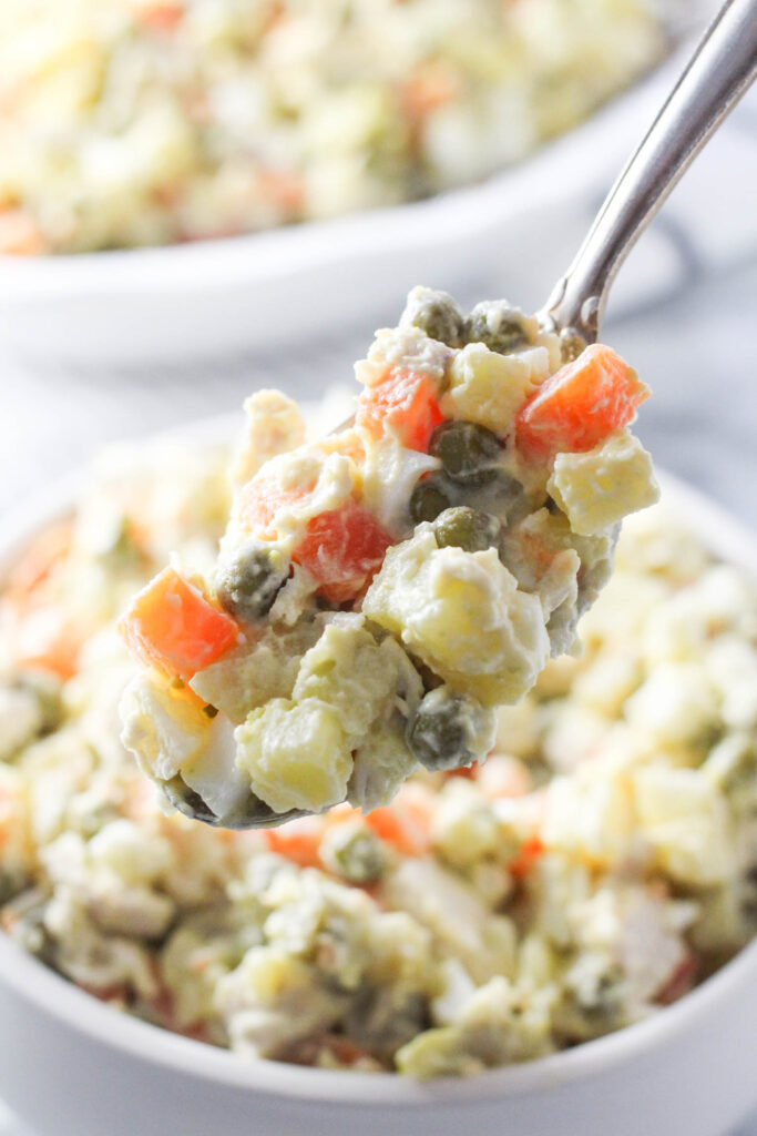 Close-up of Russian potato salad (Olivier salad) on a spoon.