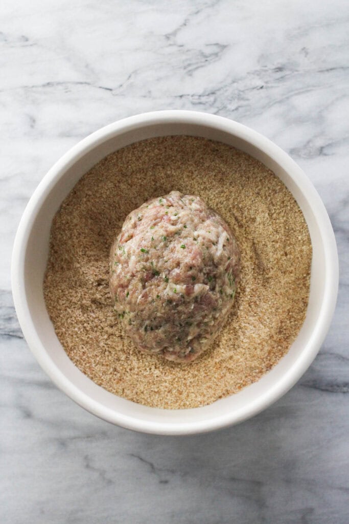 Kotlety being coated in breadcrumbs before cooking.