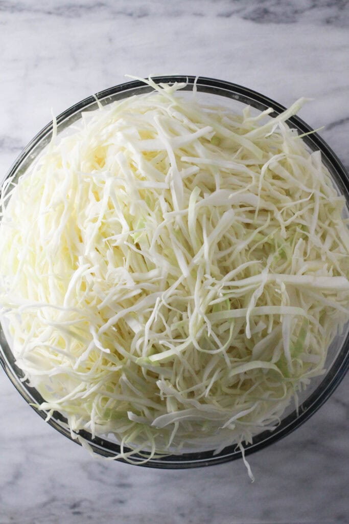 Shredded green cabbage in bowl ready for Krautsalat.