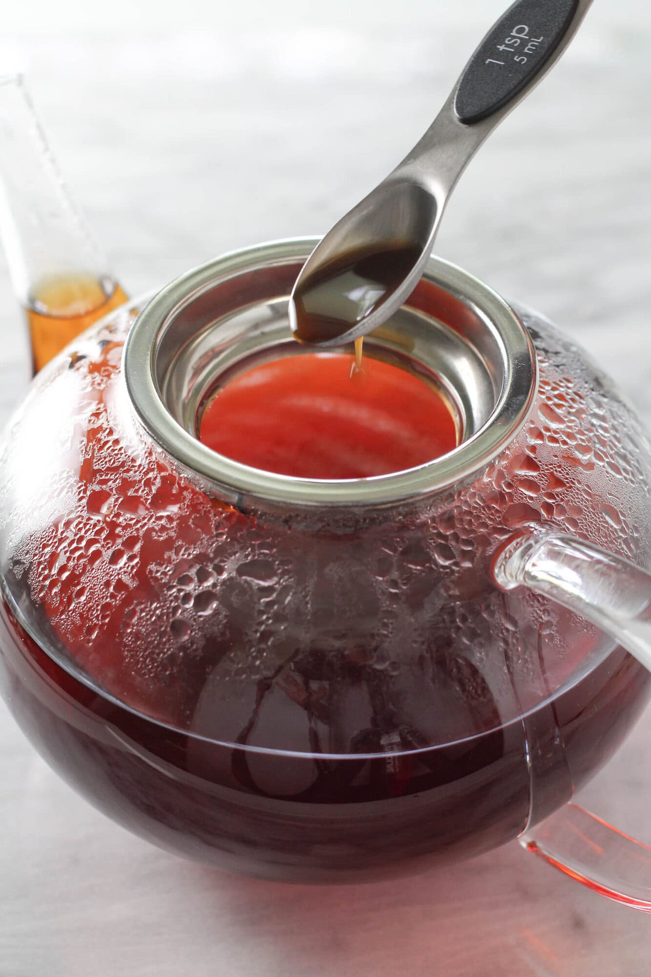 Vanilla extract being added to freshly brewed rooibos tea.