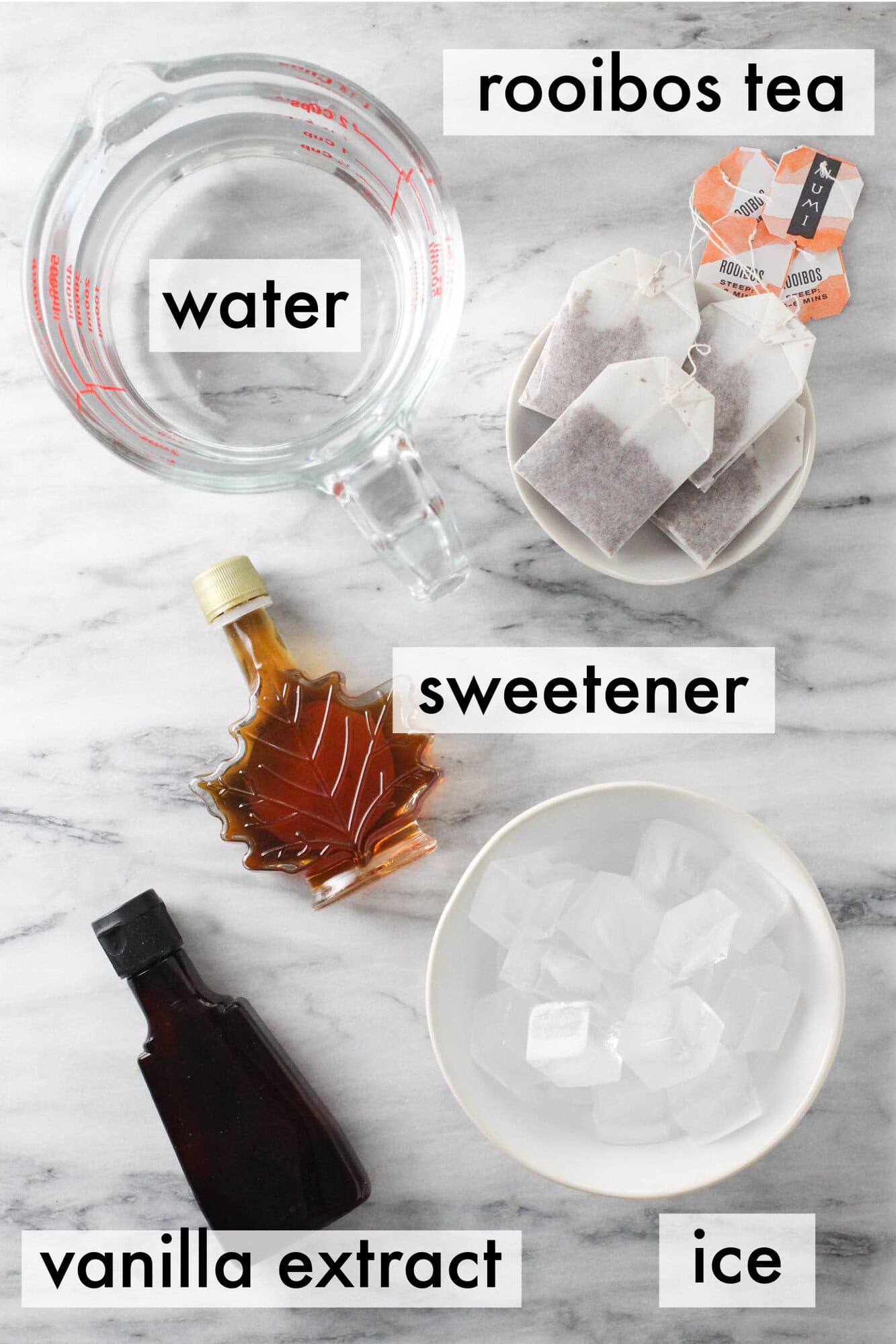 Flat lay of ingredients for vanilla iced rooibos tea including rooibos tea, vanilla extract, sweetener, water, and ice.